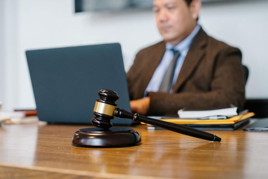 Crop concentrated Asian male judge in formal clothes sitting using modern netbook while working in law office