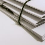Pile of white envelopes tied with a green string, showcasing a minimalist design.