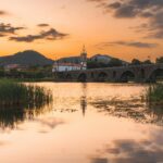 Serene sunset over Ponte de Lima, Portugal, showcasing historical bridge reflection on the river.