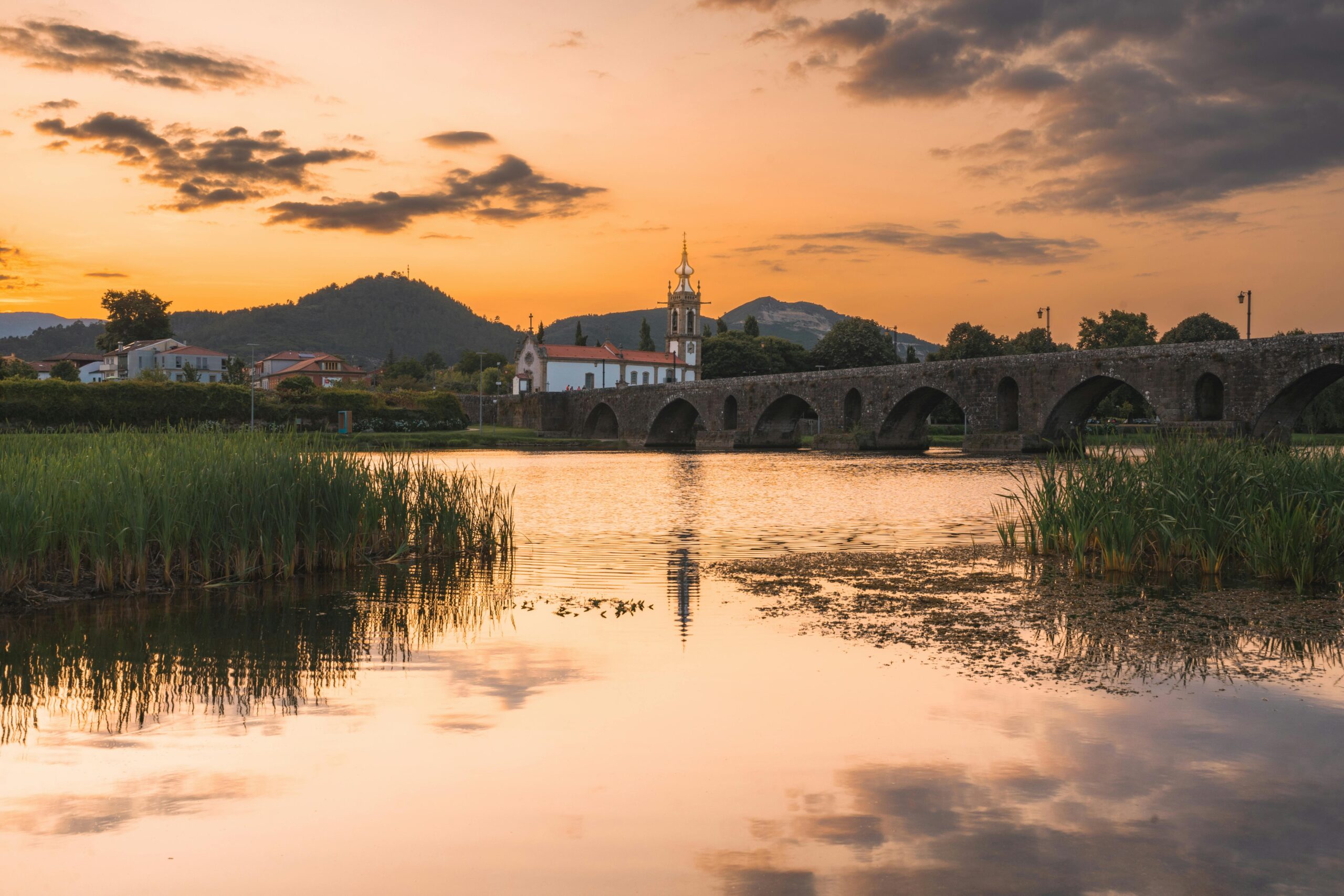 Serene sunset over Ponte de Lima, Portugal, showcasing historical bridge reflection on the river.