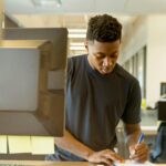 Young man intensely focused on his work at a modern tech office.