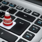 Miniature caution cone on a computer keyboard symbolizing data security and control.