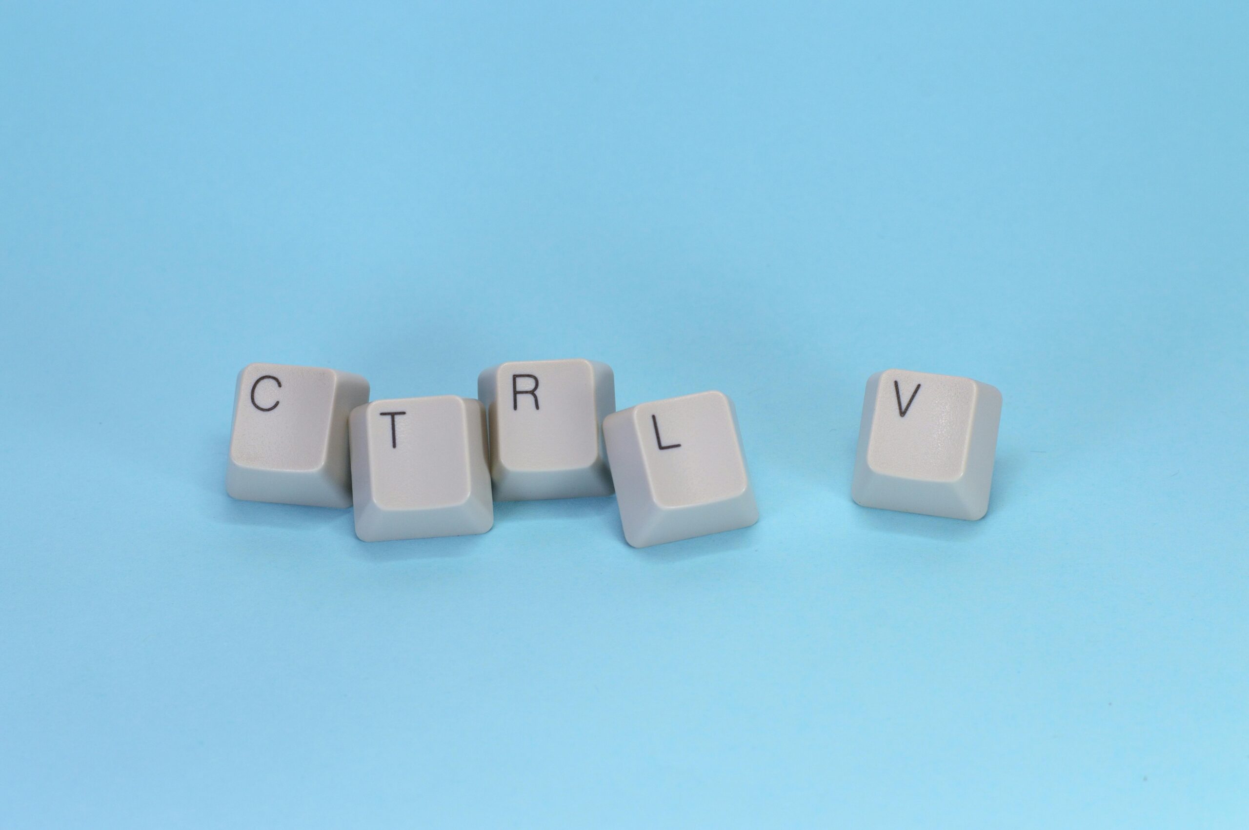 Close-up of CTRL V keyboard keys on a blue background. Minimalist tech concept.