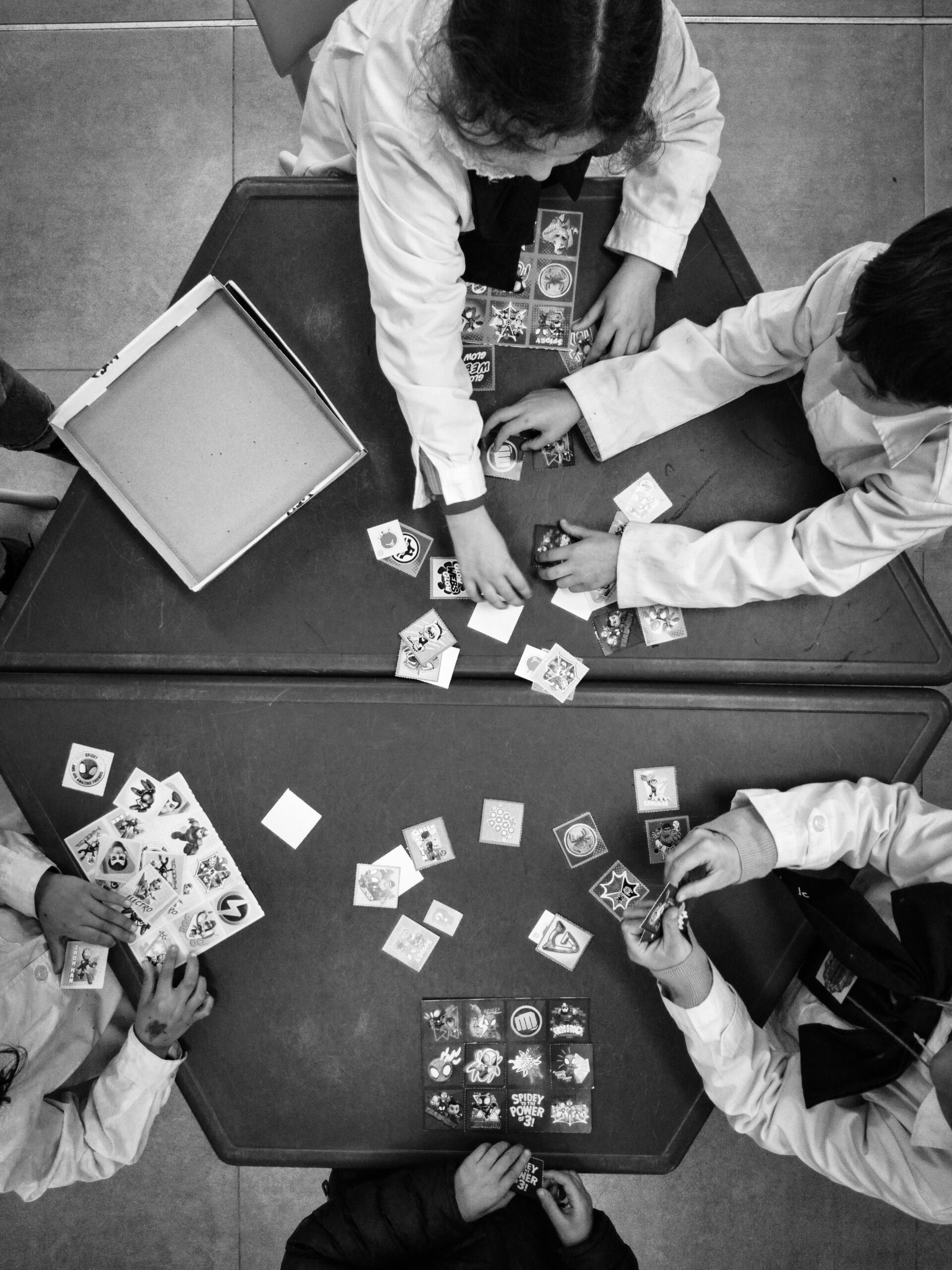 Overhead view of kids playing a card game in a lab setting, emphasizing hands-on learning.